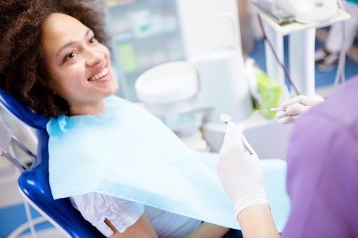 Smiling woman in dental chair looking up at dental assistant.