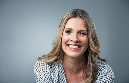 Image of a smiling middle aged woman after her dental implant restoration, at The Center for Esthetic Dentistry in Grants Pass, OR.