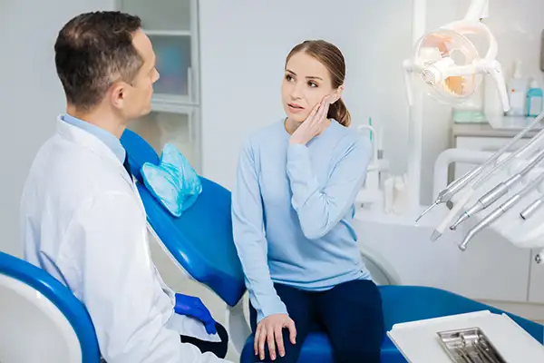 Concerned patient discussing her tooth pain with her dentist while sitting in a dental chair at The Center for Esthetic Dentistry.