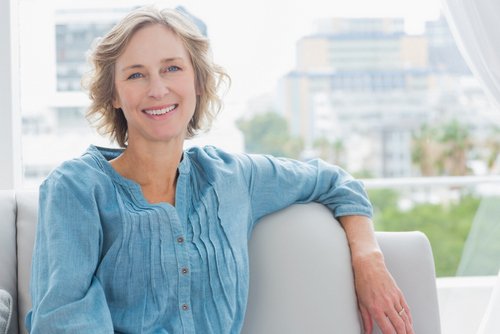 Image of an older woman smiling, on a couch, and not been to the dentist for years.