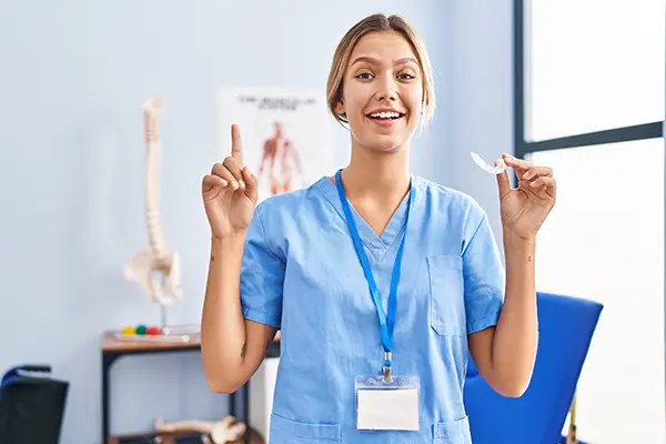 Dental assistant holding a mouth guard while explaining how it prevents bruxism.
