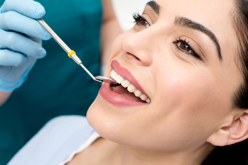 Image of a smiling woman in a dental chair, showing teeth up close.